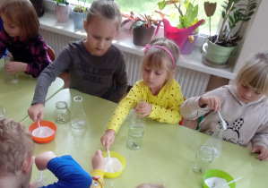Dzieci wsypują łyżeczką sól do słoiczków